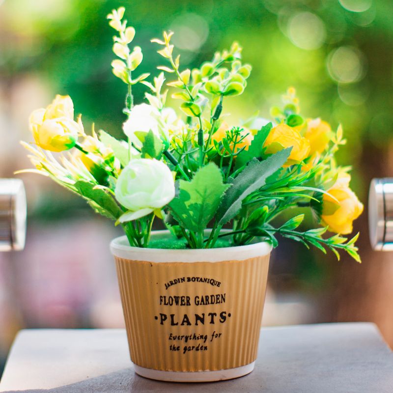 Artificial flower arrangement in a white pot on a white table